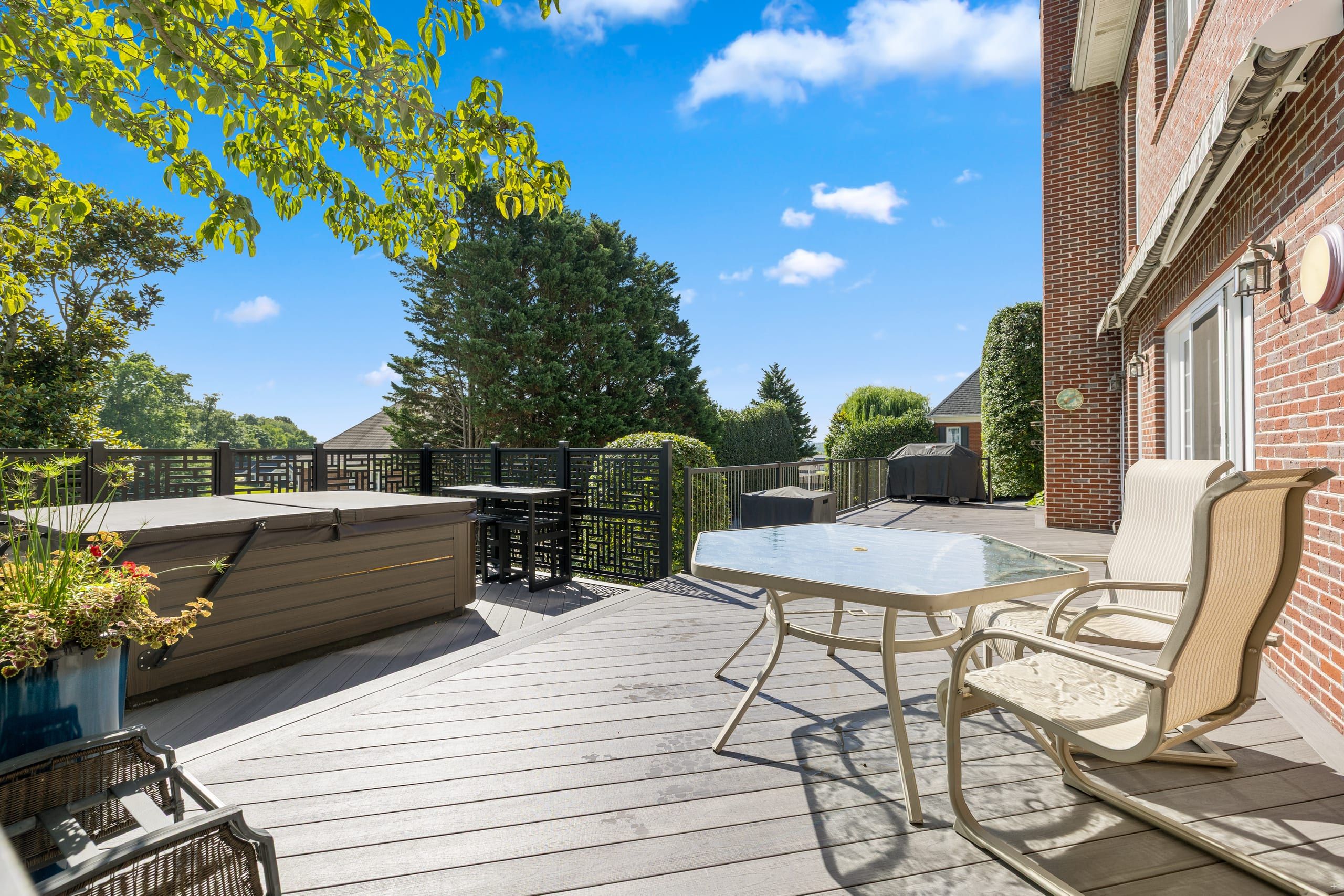 Wilshire hot tub and bar-height seating with decorative privacy screens and patio dining on gray composite decking