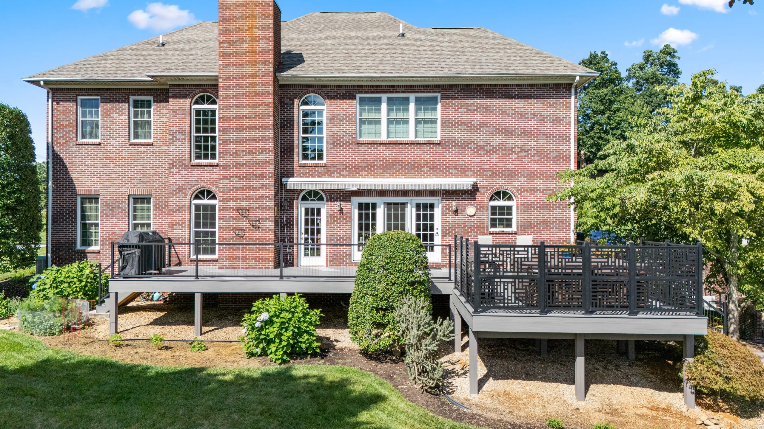 Full rear elevation of the Wilshire two-story brick home with its wraparound composite deck and cable railing