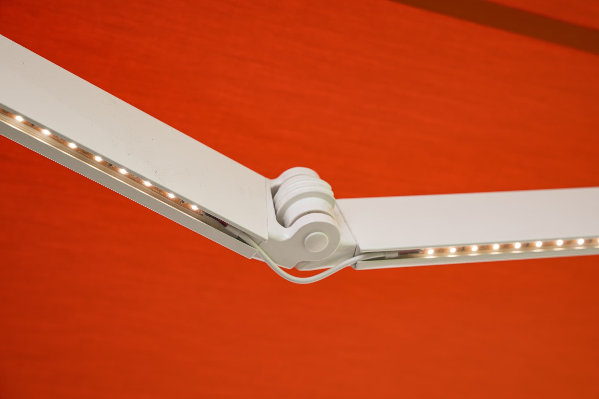 Close-up of a white SunPro awning arm with integrated LED lighting illuminated