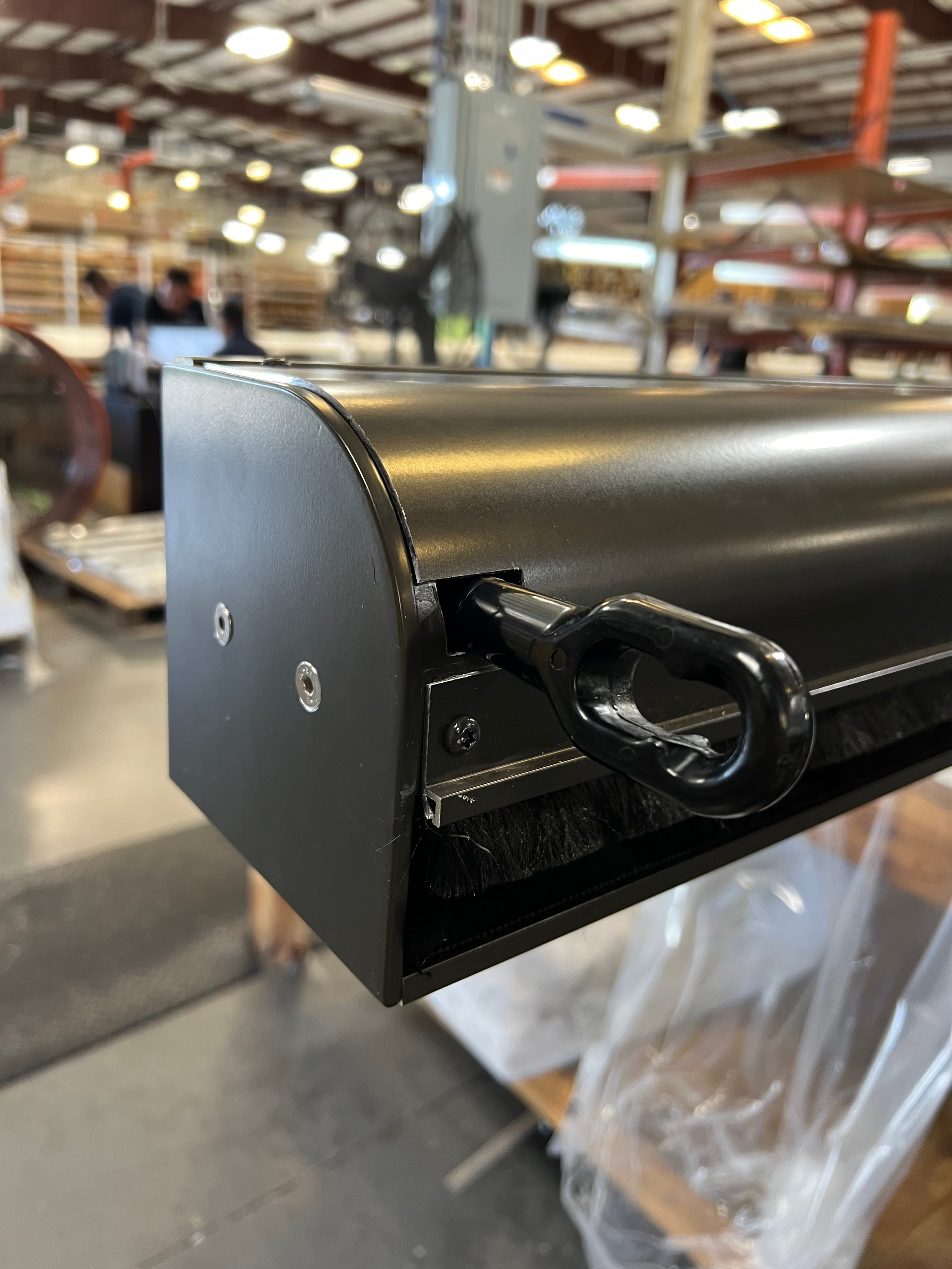 Corner view of a manual SunPro screen with bronze housing and pull-ring bottom bar hardware
