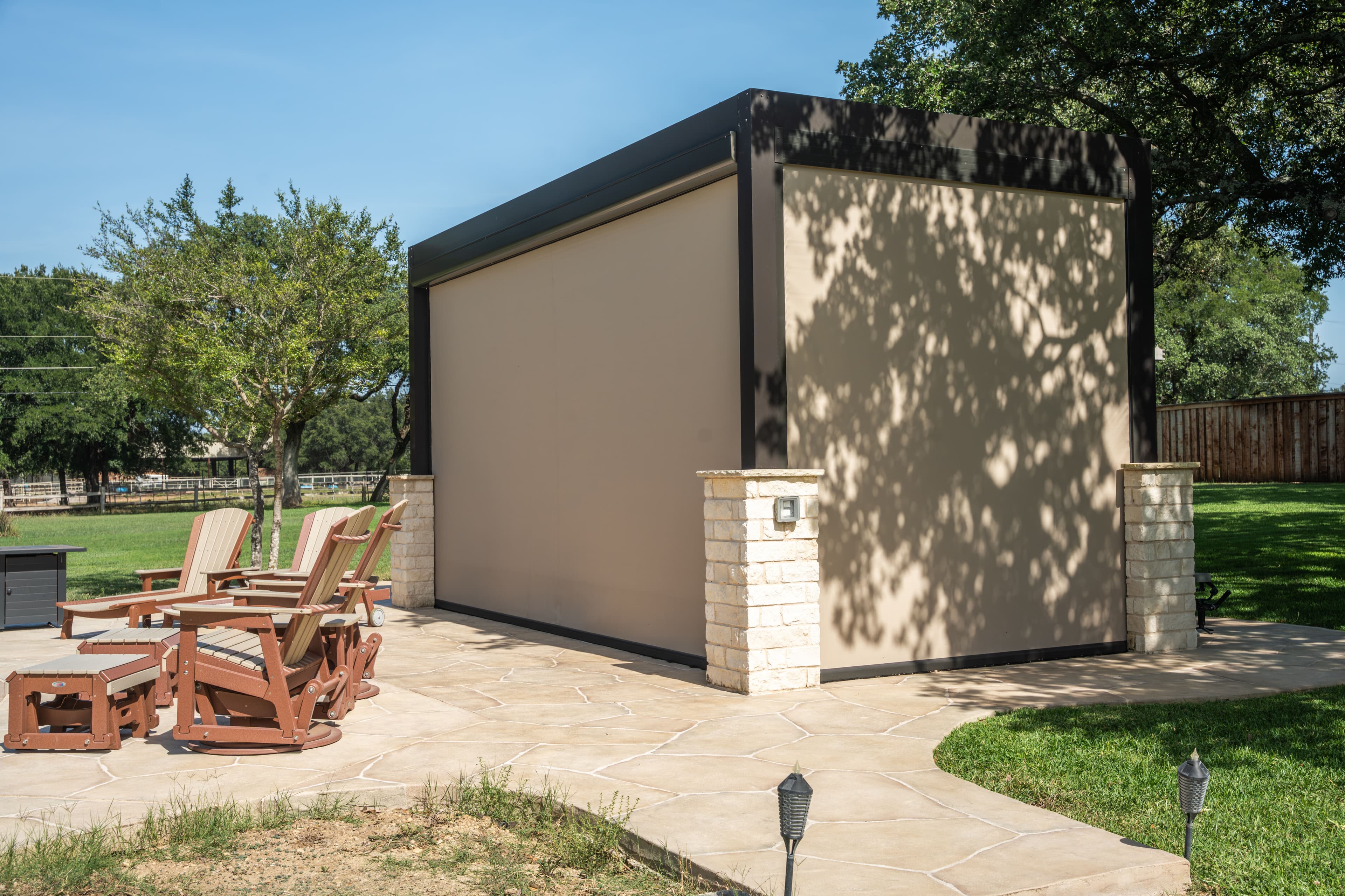 Freestanding pergola enclosed with retractable screens beside a backyard patio and pool